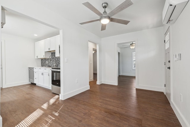 unfurnished living room with ceiling fan, an AC wall unit, and dark hardwood / wood-style flooring