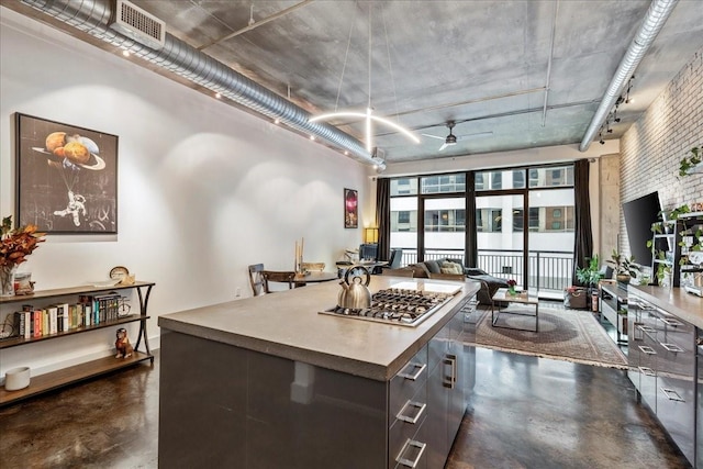 kitchen with a kitchen island, a high ceiling, stainless steel gas cooktop, ceiling fan, and dark brown cabinets