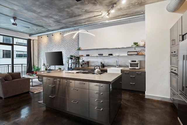 kitchen featuring appliances with stainless steel finishes, brick wall, a center island, and sink