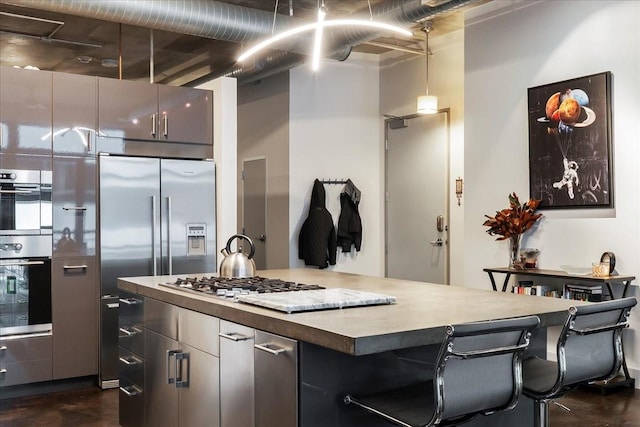 kitchen featuring a kitchen island, a breakfast bar area, pendant lighting, and appliances with stainless steel finishes