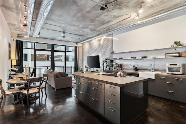 kitchen featuring dark brown cabinetry, sink, a kitchen island, ceiling fan, and stainless steel gas stovetop