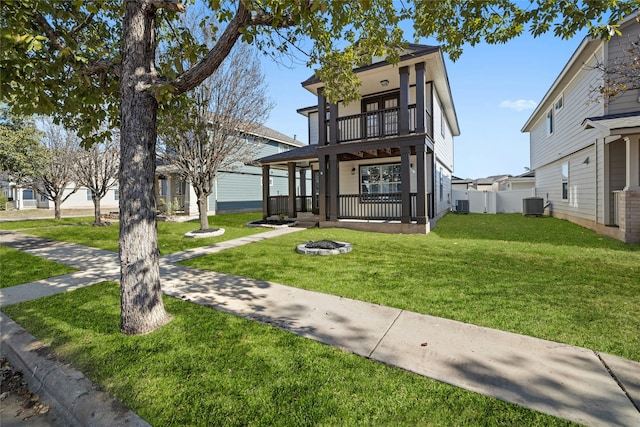 view of front of property featuring cooling unit, a balcony, an outdoor fire pit, and a front lawn