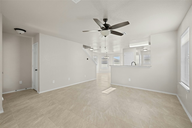 unfurnished living room featuring ceiling fan with notable chandelier