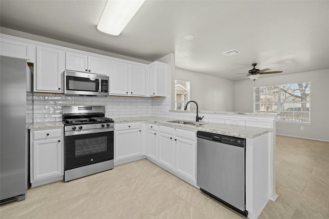 kitchen with stainless steel appliances, kitchen peninsula, sink, and white cabinets