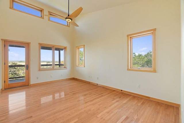 unfurnished room with light hardwood / wood-style floors, ceiling fan, and a high ceiling