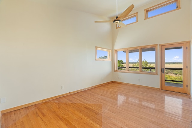 unfurnished room with a high ceiling, ceiling fan, and light wood-type flooring