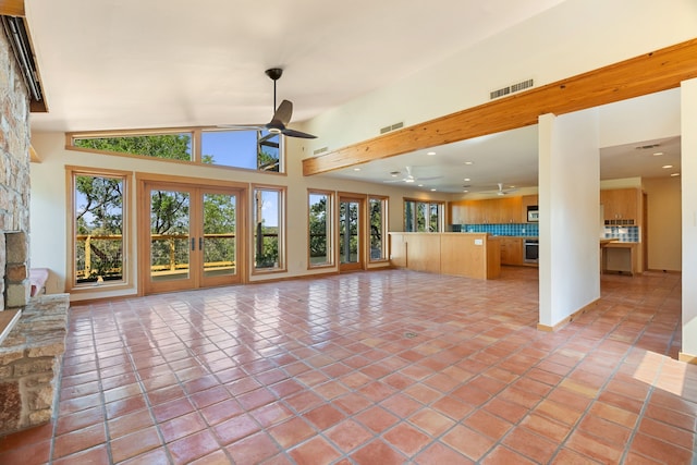 unfurnished living room with french doors, ceiling fan, vaulted ceiling, and light tile patterned floors