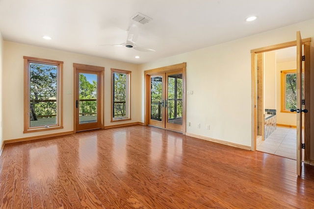 unfurnished room featuring ceiling fan, a wealth of natural light, light hardwood / wood-style floors, and french doors