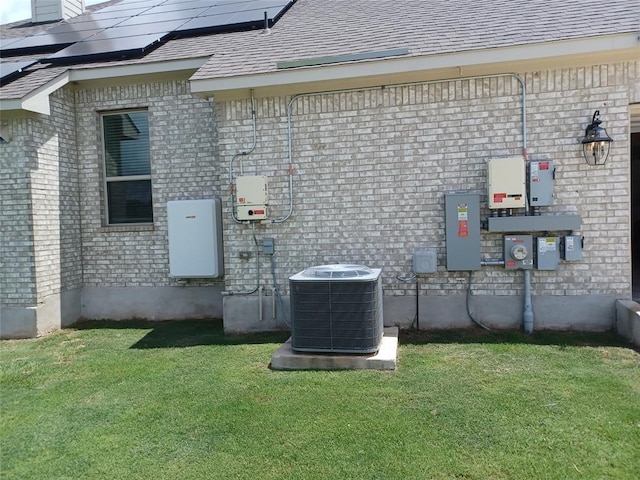 view of side of property featuring a yard, central AC, and solar panels