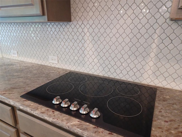 kitchen with black electric cooktop, tasteful backsplash, and light stone countertops