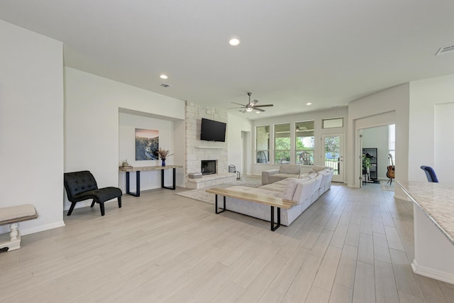 living room with ceiling fan, light wood-type flooring, and a fireplace