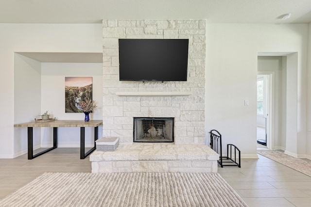 living room with a stone fireplace and light hardwood / wood-style flooring