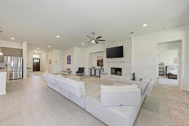 living room with ceiling fan and a stone fireplace