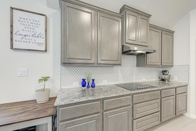 kitchen featuring black electric stovetop, light stone countertops, vaulted ceiling, and backsplash