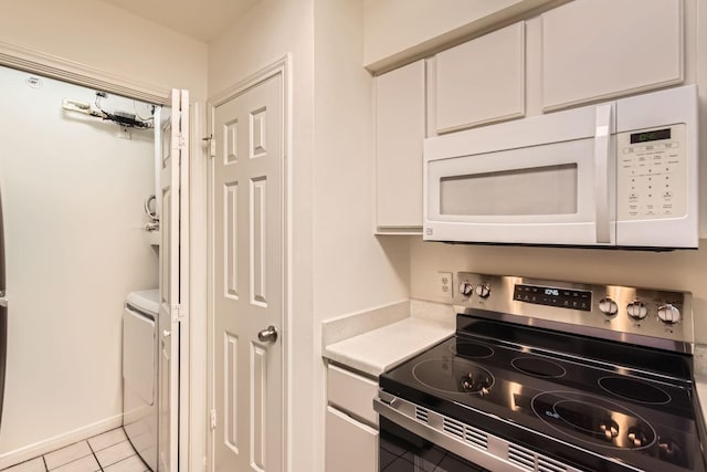 kitchen with white cabinets, washer / dryer, light tile patterned floors, and stainless steel range with electric cooktop