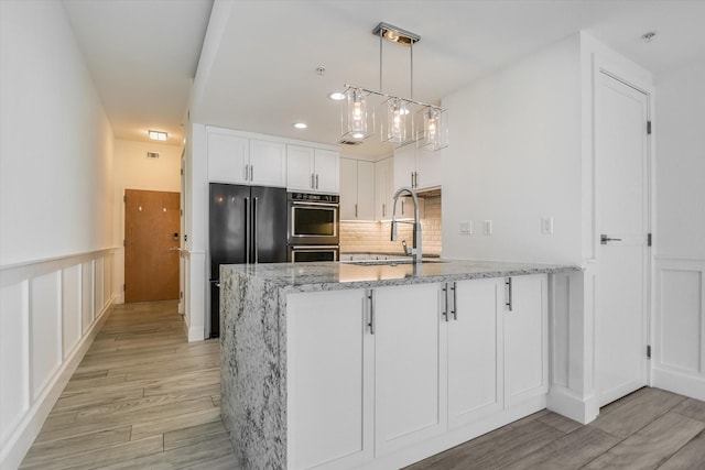 kitchen with black refrigerator, pendant lighting, white cabinetry, sink, and kitchen peninsula