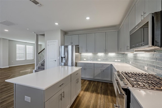 7001 Lewiston Way, Austin, TX 78724 - kitchen with stainless steel appliances, dark wood finished floors, gray cabinetry, backsplash, and recessed lighting