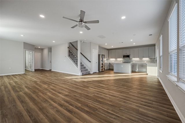 unfurnished living room featuring dark wood-type flooring, sink, and ceiling fan