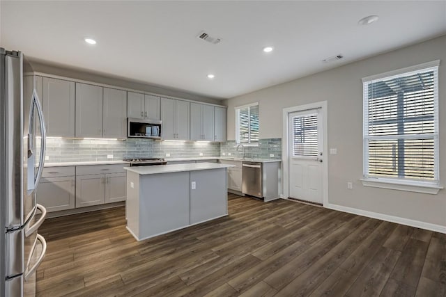 7001 Lewiston Way, Austin, TX 78724 - kitchen with stainless steel appliances, decorative backsplash, dark wood-style flooring, a kitchen island, and light countertops