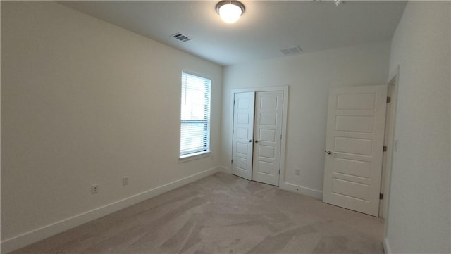 unfurnished bedroom with light colored carpet and a closet