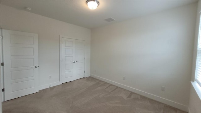 unfurnished bedroom with light carpet and a closet