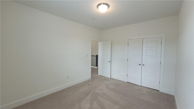 unfurnished bedroom featuring light carpet and a closet