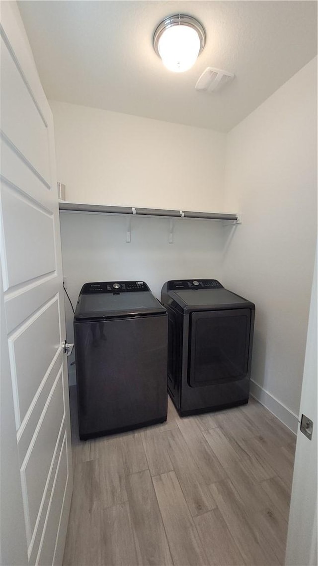 laundry area with light hardwood / wood-style flooring and washer and dryer