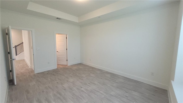 12320 Maypole Bnd, Austin, TX 78717 - unfurnished bedroom with a tray ceiling, light wood-style flooring, and baseboards
