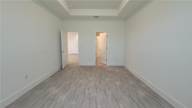 unfurnished bedroom with a tray ceiling and light hardwood / wood-style flooring