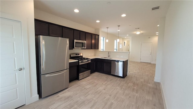 12320 Maypole Bnd, Austin, TX 78717 - kitchen with appliances with stainless steel finishes, light countertops, light wood finished floors, recessed lighting, and a peninsula