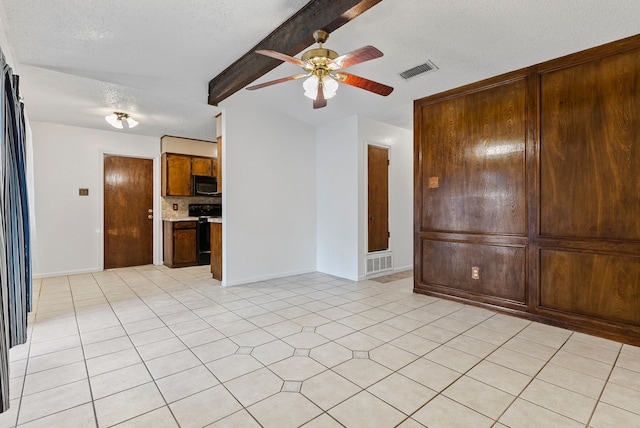 spare room featuring beamed ceiling, ceiling fan, and a textured ceiling