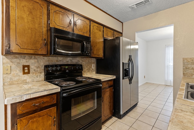 kitchen featuring sink, tasteful backsplash, a textured ceiling, light tile patterned floors, and black appliances