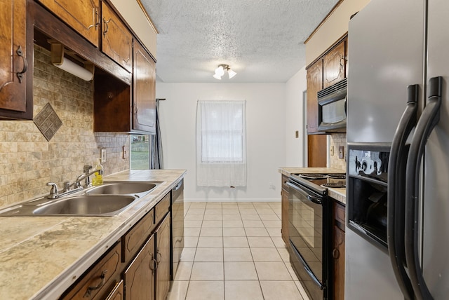 kitchen featuring tasteful backsplash, sink, light tile patterned floors, black appliances, and a textured ceiling