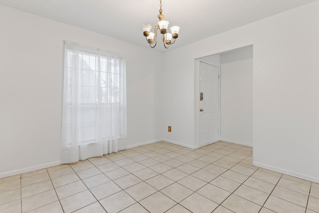 unfurnished room featuring light tile patterned floors, a chandelier, and a textured ceiling