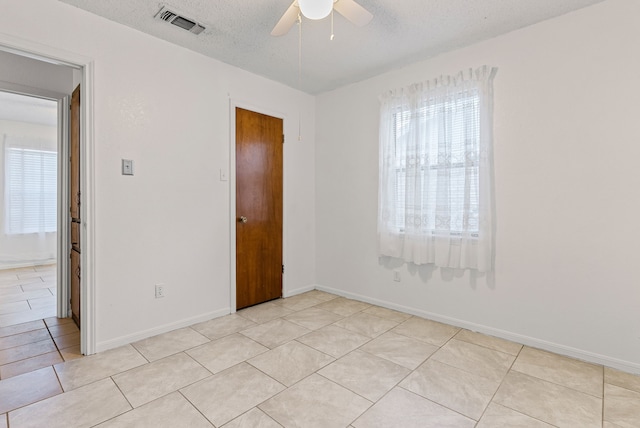 empty room featuring ceiling fan, a textured ceiling, and light tile patterned floors