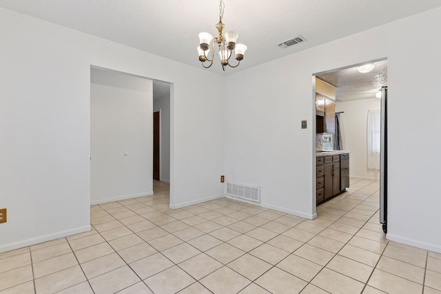 tiled empty room featuring an inviting chandelier and a textured ceiling