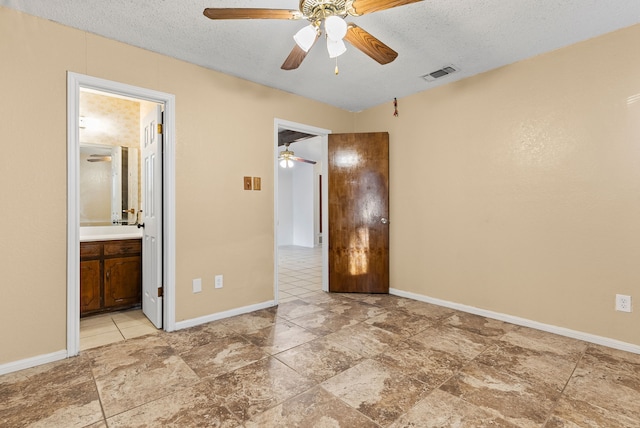 unfurnished bedroom featuring ceiling fan, ensuite bath, and a textured ceiling