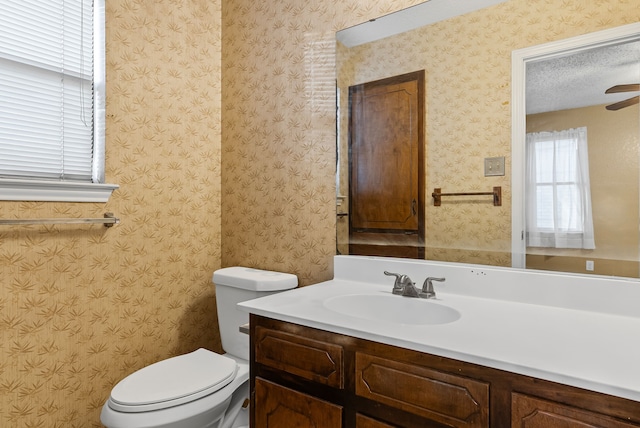 bathroom with ceiling fan, vanity, toilet, and a textured ceiling