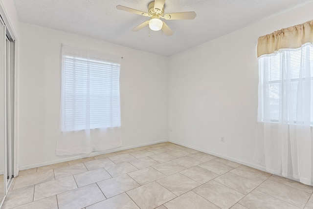 unfurnished room featuring ceiling fan, a textured ceiling, a healthy amount of sunlight, and light tile patterned flooring