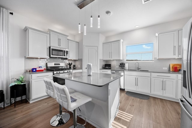 kitchen featuring sink, stainless steel appliances, a center island, and white cabinets