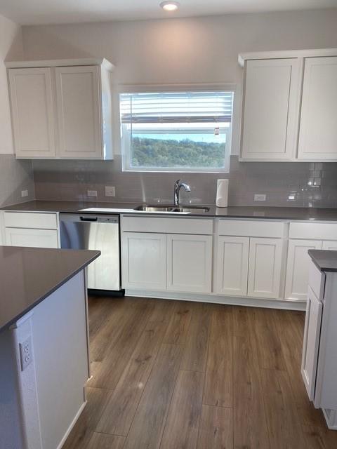 kitchen featuring sink, white cabinetry, dark hardwood / wood-style floors, dishwasher, and backsplash