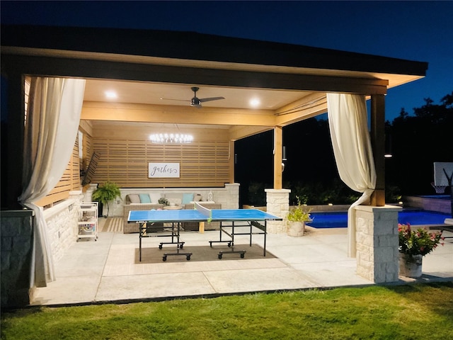 patio at night featuring a pool and ceiling fan