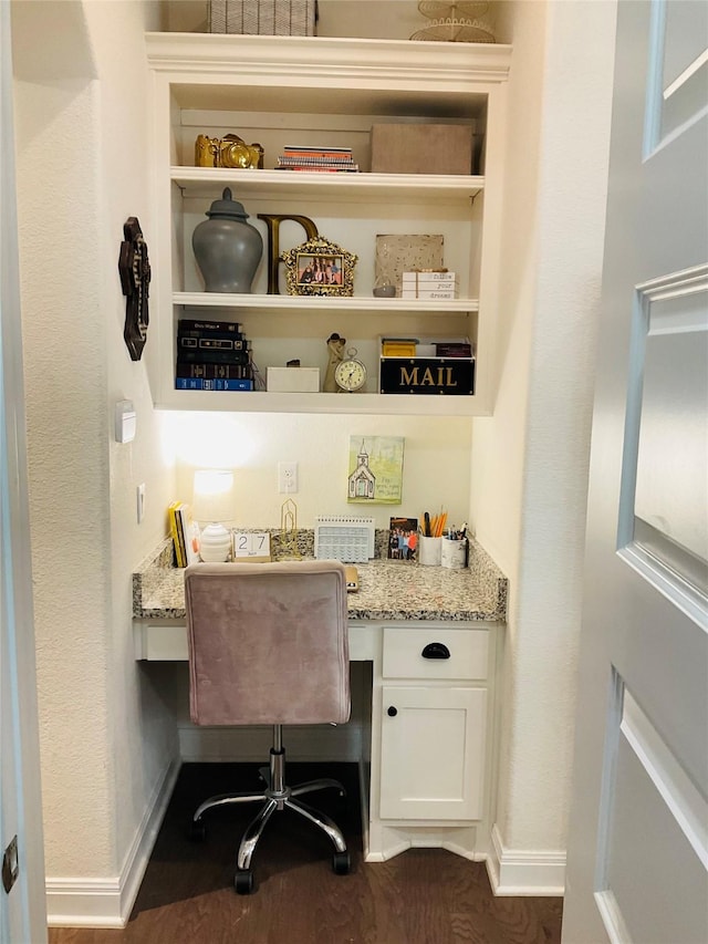 home office with built in desk and dark hardwood / wood-style flooring