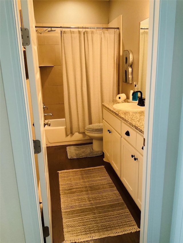 full bathroom featuring hardwood / wood-style flooring, vanity, shower / bath combination with curtain, and toilet