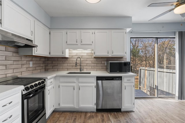 kitchen with dark wood-type flooring, sink, appliances with stainless steel finishes, white cabinets, and backsplash