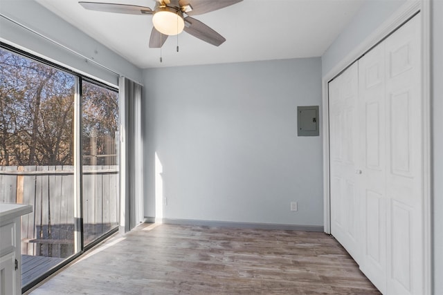 interior space featuring light wood-type flooring, electric panel, ceiling fan, and a closet