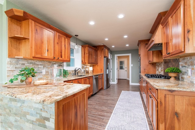 kitchen with light stone counters, decorative light fixtures, appliances with stainless steel finishes, light hardwood / wood-style floors, and decorative backsplash