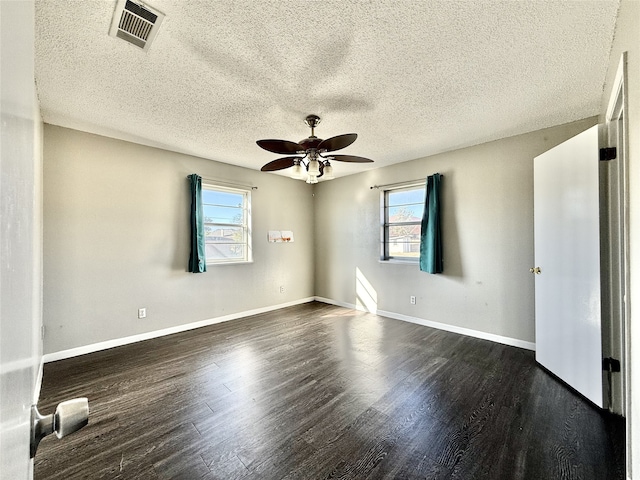 spare room with a healthy amount of sunlight, dark wood-type flooring, a textured ceiling, and ceiling fan