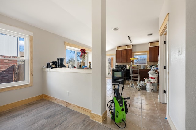 kitchen featuring black electric range oven, a wealth of natural light, and vaulted ceiling