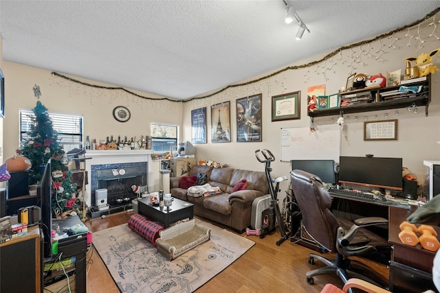 office featuring a fireplace, wood-type flooring, rail lighting, and a textured ceiling